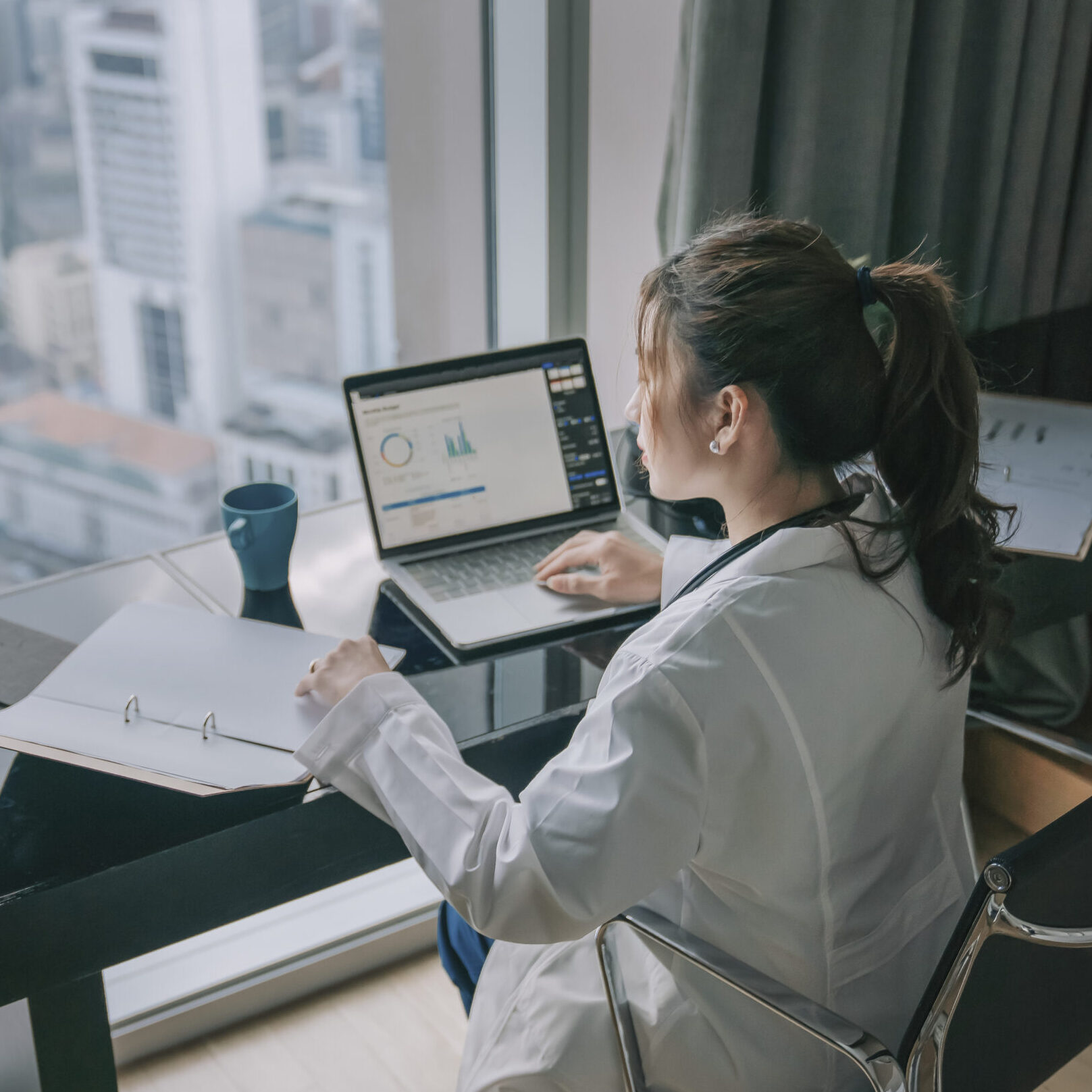 asian chinese female doctor working on medical report with laptop and document file