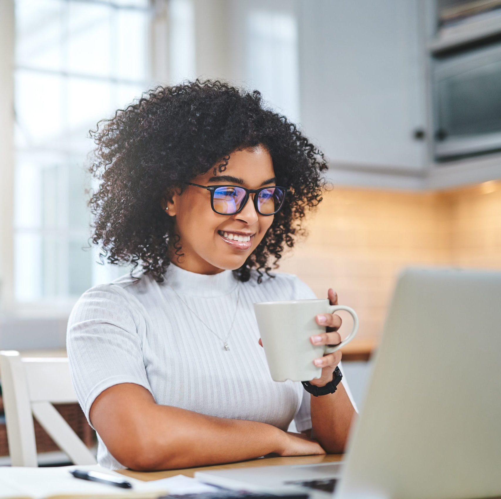 Shot of a young woman using a laptop and having coffee while working from
